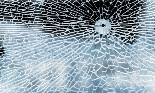 Broken glass with bullet hole, cracks